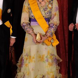 Look de la reina Sofía con vestido de gala largo en color amarillo pastel con llamativos detalles florales en tonos morados y amarillo intenso