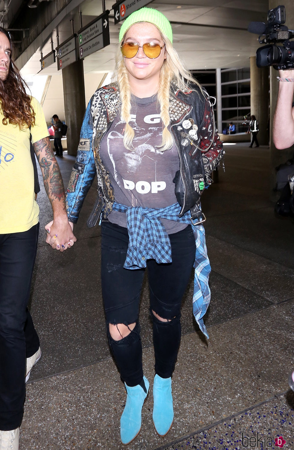 Kesha con camiseta estampada, jeans negros y botines azules