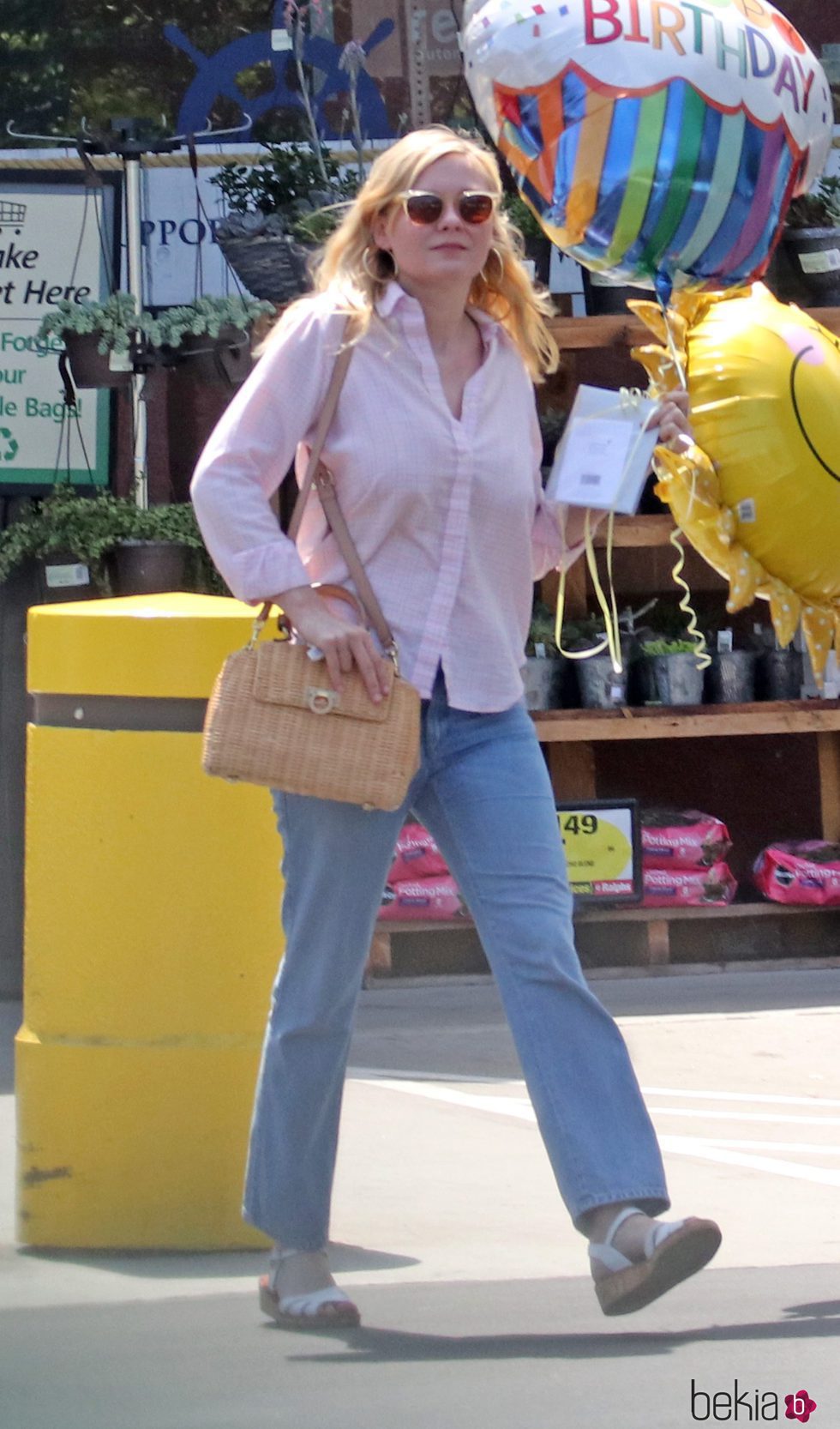 Kirsten Dunts con camisa rosa y pantalones vaqueros anchos
