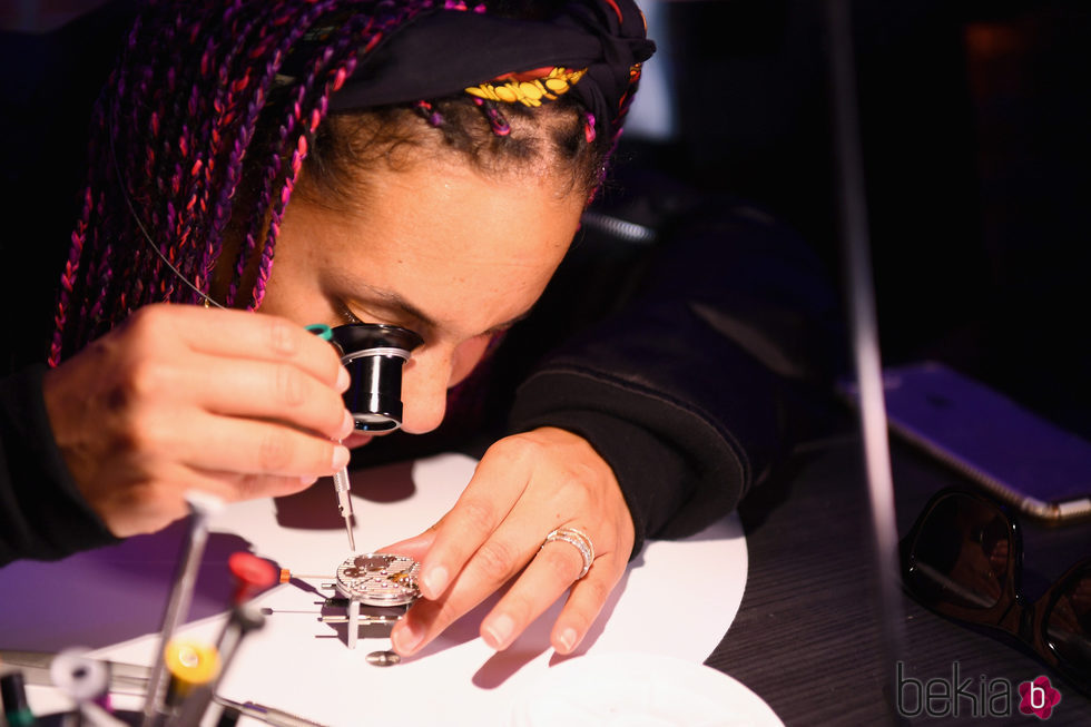 Alicia Keys observando la maquinaria de los relojes Zenith en el evento benéfico en Nueva York
