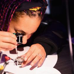 Alicia Keys observando la maquinaria de los relojes Zenith en el evento benéfico en Nueva York