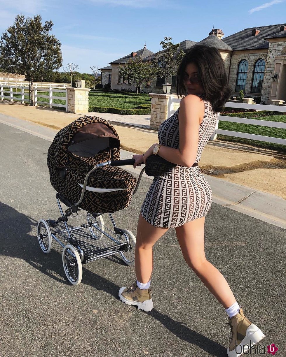 Kylie Jenner llevando a su hija Stormi en un carrito de Fendi a juego con su vestido