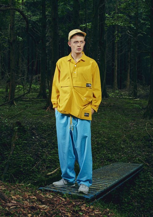 Modelo con un pantalón azul y camisa amarilla de la nueva línea de Outdoor de la nueva colección SS19 de Woolrich