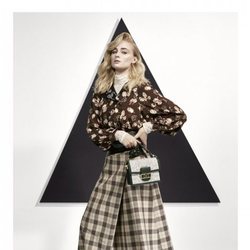 Sophie Turner con una blusa estampada y una falda midi posando para el lookbook Pre-Fall 2019 de Louis Vuitton