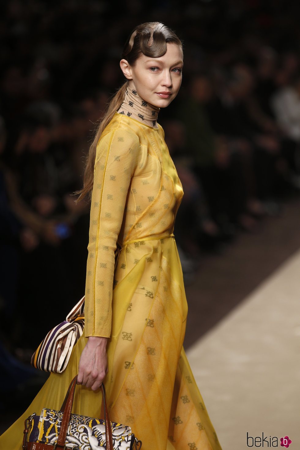 Gigi Hadid con un vestido amarillo superpuesto a un body en el desfile otoño/invierno 2019/2020 de Fendi