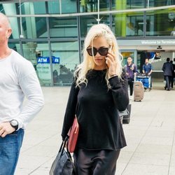 Rita Ora con look 'total black' de vestido satinado en el aeropuerto de Heathrow
