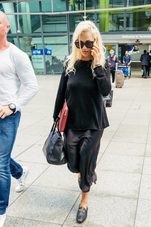 Rita Ora con look 'total black' de vestido satinado en el aeropuerto de Heathrow