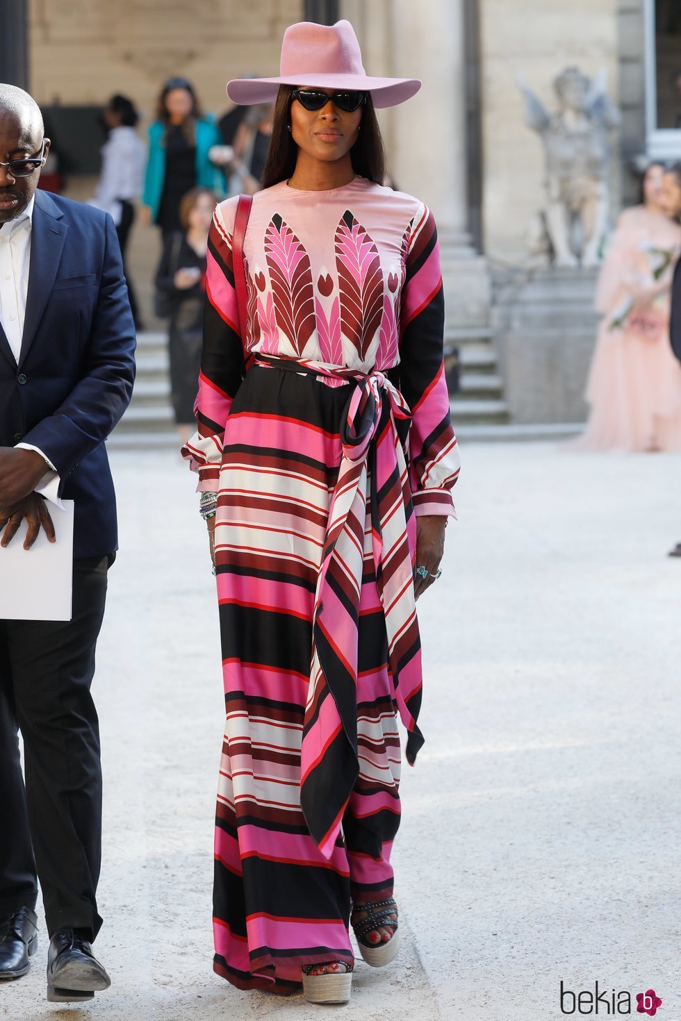 Naomi Campbell con un vestido de estampado asimétrico morado y rosa en la Fashion Week de París