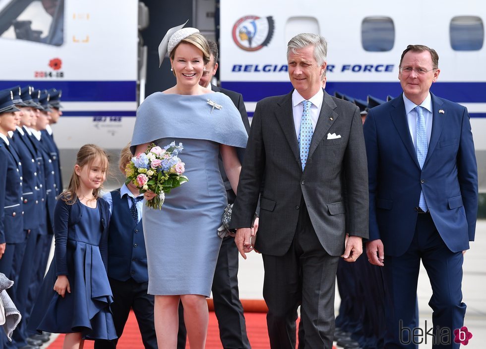 La Reina Matilde de Bélgica con un vestido con capa de color lila aterriza en el aeropuerto de Sajonia