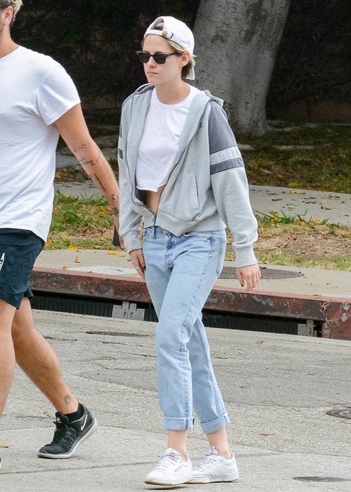 Kristen Stewart con un look sporty chic de lujo con vaqueros lavados rectos y crop top con sudadera de cremallera en Los Ángeles