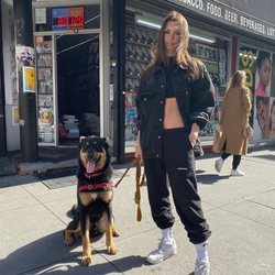 Emily Ratajkowski con un look total black sport paseando a su perro por Nueva York