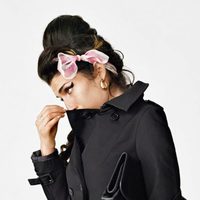 Amy Winehouse con un abrigo negro y lazo rosa para Fred Perry