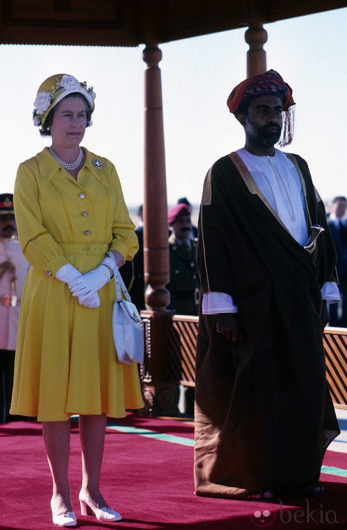 La Reina Isabel II con vestido lady amarillo y sombrero de flores