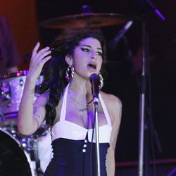 Amy Winehouse con un vestido blanco y negro en un concierto
