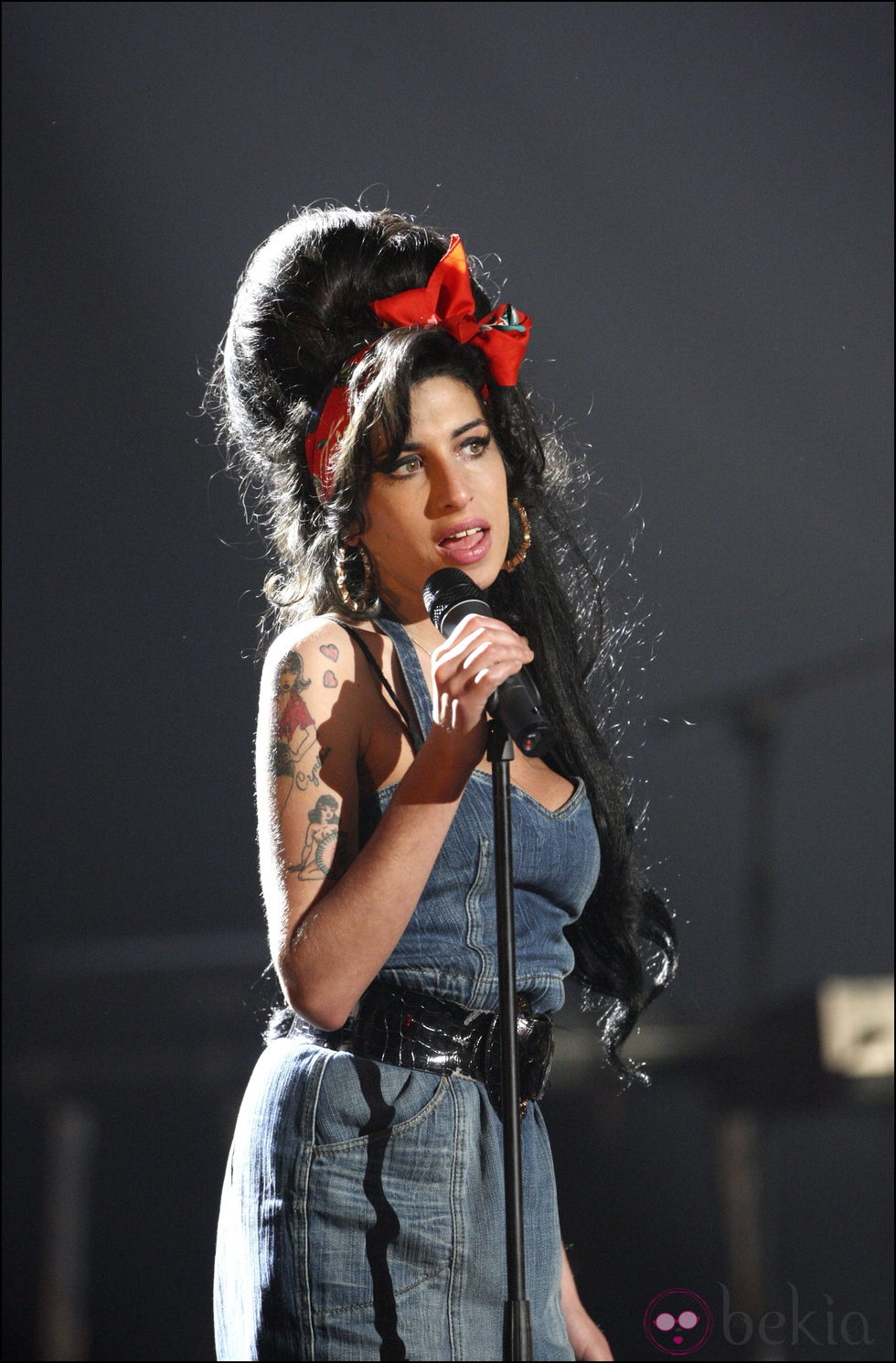 Amy Winehouse con un vestido denim y pañuelo en la cabeza