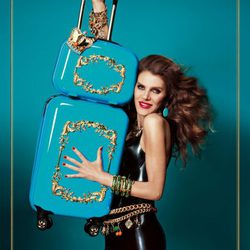 Anna Dello Russo posando con dos maletas de su colección para H&M