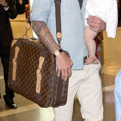 David Beckham con un pantalón de color crema, camisa azul y cartera de Louis Vuitton