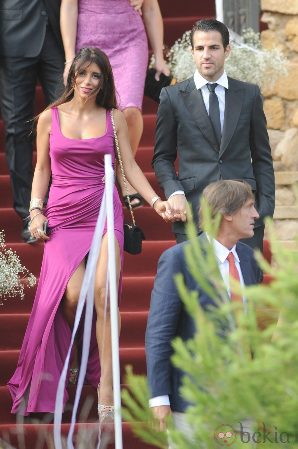 Daniella Semaan con un vestido fucsia acompañada de Cesc Fàbregas