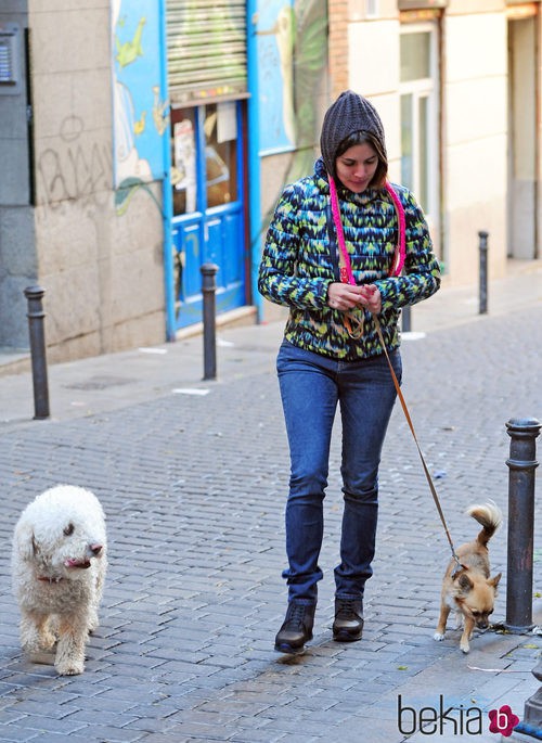 Adriana Ugarte con vaqueros y abrigo de colores paseando a sus perros