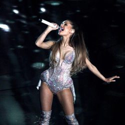 Ariana Grande con un body plateado con incrustaciones brillantes y botas altas a juego