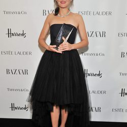 Marion Cotillard con vestido negro sujetando premio a la mujer del año de Harper
