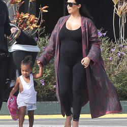 Kim Kardashian con ajustado jumpsuit negro y kimono granate en su segundo embarazo