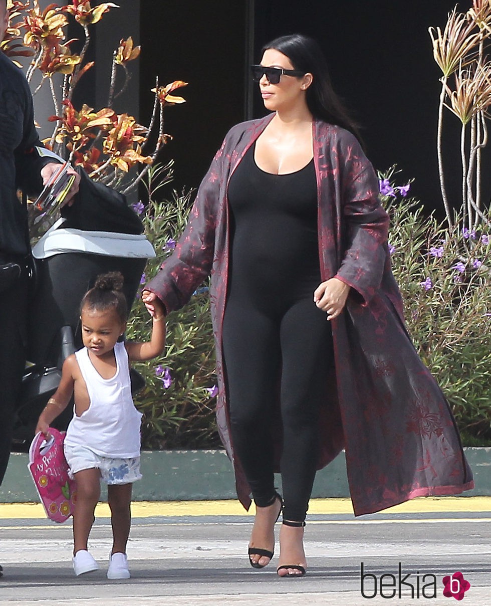 Kim Kardashian con ajustado jumpsuit negro y kimono granate en su segundo embarazo