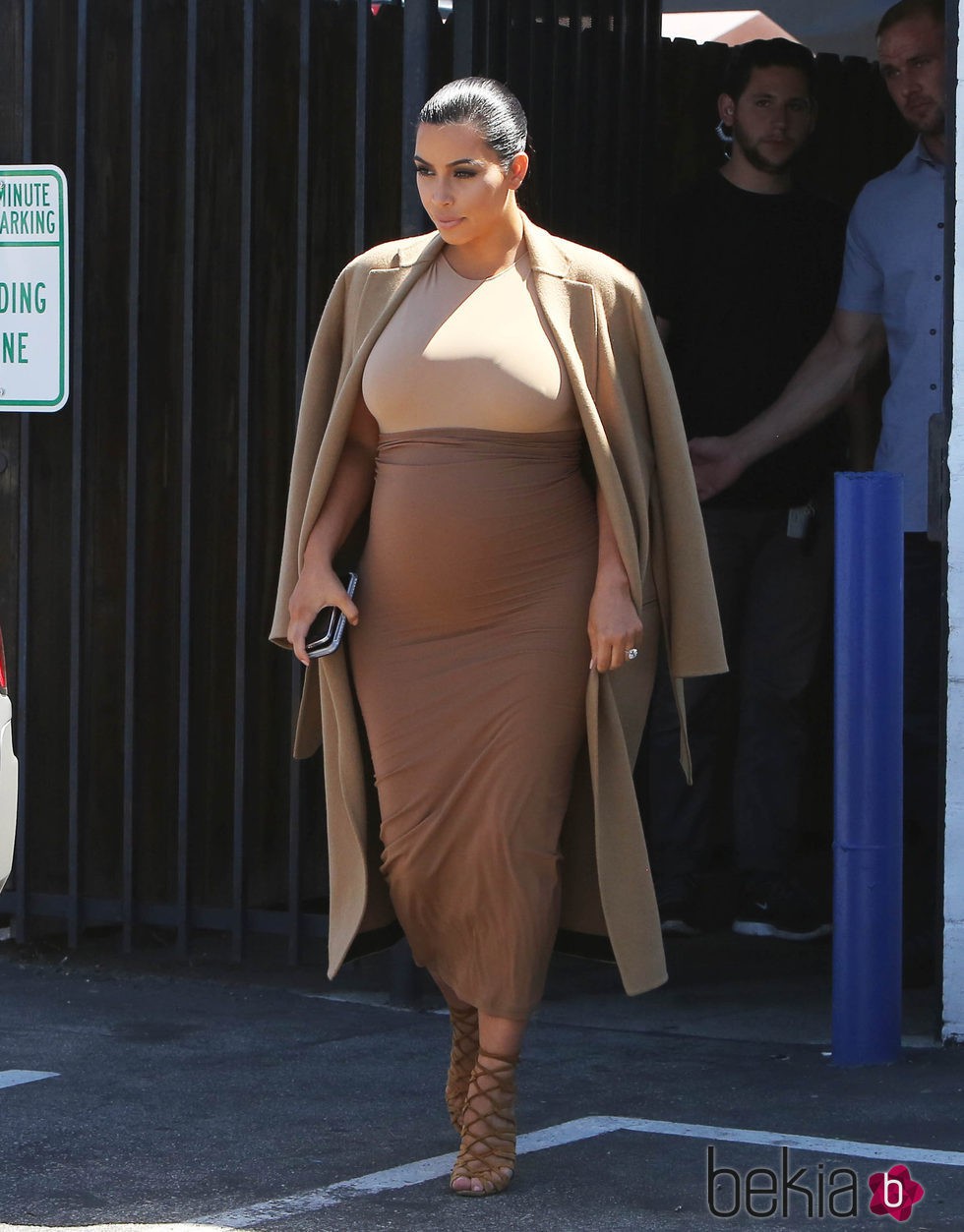 Kim Kardashian con vestido y abrigo en tonos tierra en su segundo embarazo