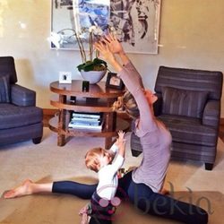 Gisele Bündchen con mallas azul marino y camiseta lila haciendo yoga con su hija Vivian
