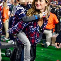 Gisele Bundchen con camisa de cuadros y vaqueros en un partido de la Super Bowl con su hijo