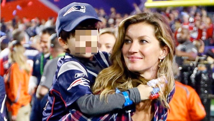 Gisele Bundchen con camisa de cuadros y vaqueros en un partido de la Super Bowl con su hijo