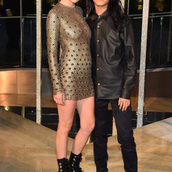 Anna Ewer junto a Alexander Wang con mini vestido ajustado en dorado y botas militares negras