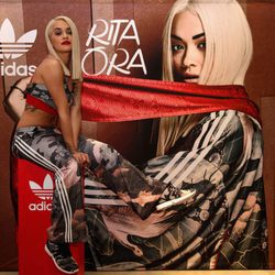 Rita Ora con ropa deportiva posando con el cartel de la nueva campaña para Adidas