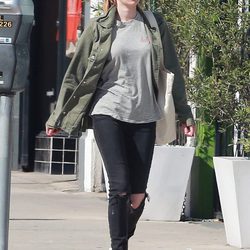 Emma Roberts con abrigo verde militar, pantalón roto y camisa a rayas