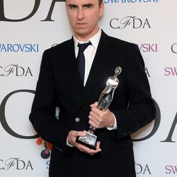 Raf Simons posando con un premio en la celebración de los CFDA Fashion Awards 2014